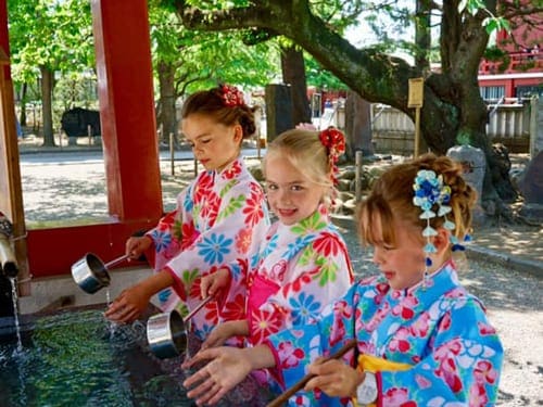 Three girls in traditional Japanese dress exploring Tokyo, one of the best places to visit in Asia with kids.