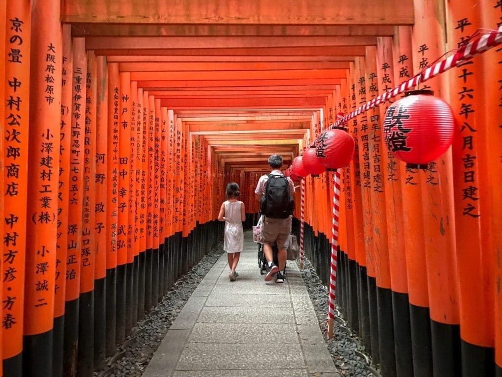 A father and his child walk down Fushimilnari Shrine in Kyoto, one of the best places to visit in Asia with kids.