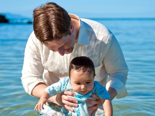 A dad looks down at his young son, while swimming in Antigua.