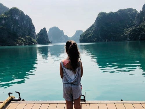 A young girl stands on a dock looking out onto Ha Long Bay, one of the best places to visit in Asia with kids.
