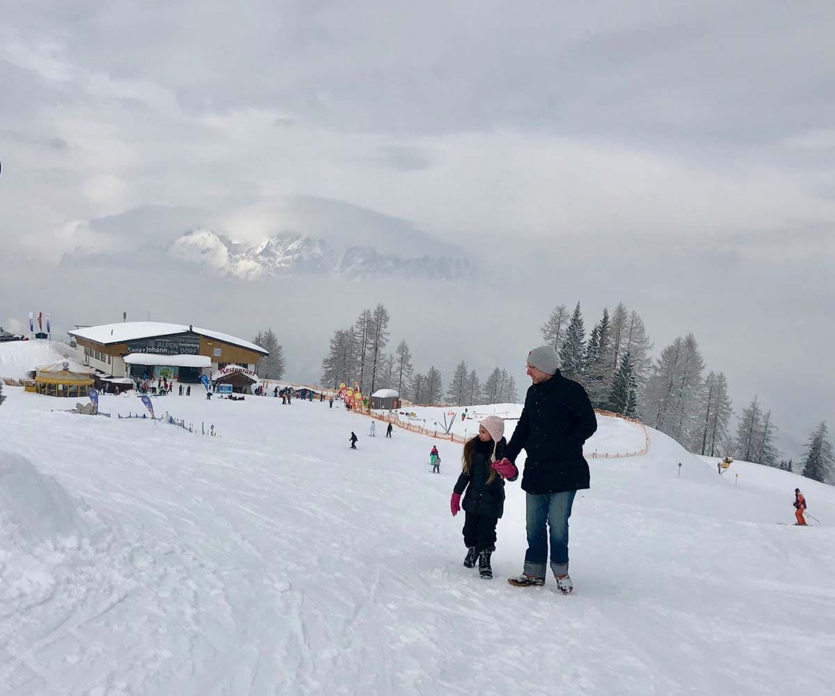 Father and daughter walk along a ski hill in Alpendorf, Austria.