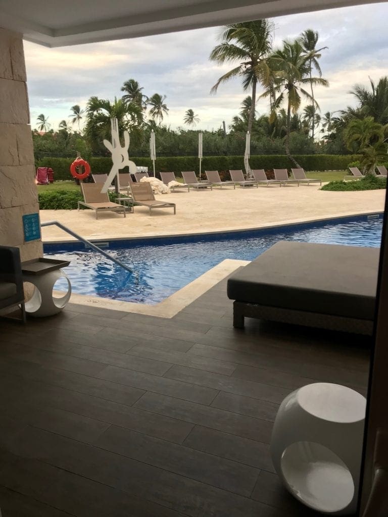 A view from the patio of a swim-up room at Nickelodeon Resort Punta Cana, featuring a pool, sitting area, and poolside lounger at one of the best all-inclusive resorts in the Caribbean for families.