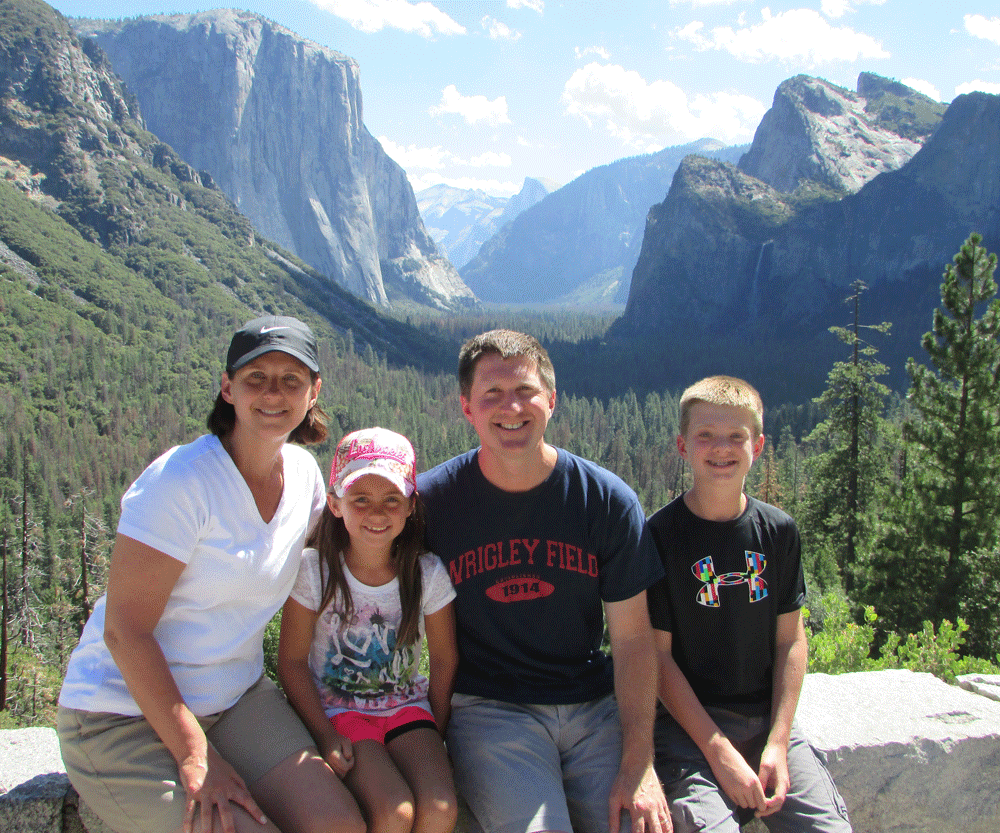 Family posing on stone wall at Yosemite National Park, one of the best places to visit in California with kids!