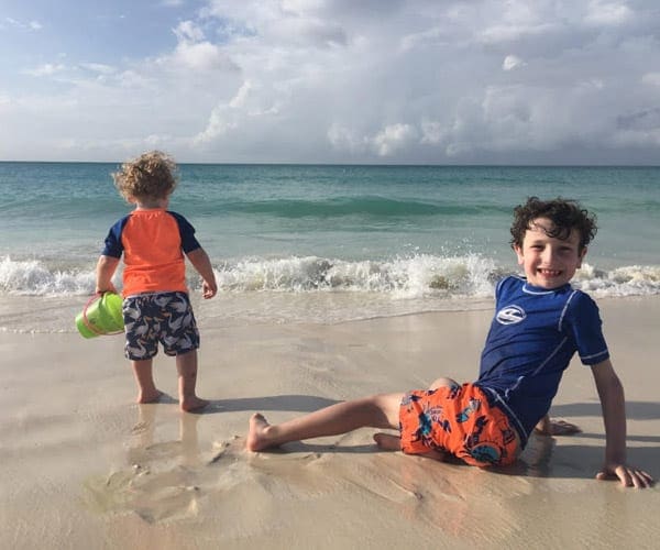Two boys play on the beach in Aruba, splashing in the waves.