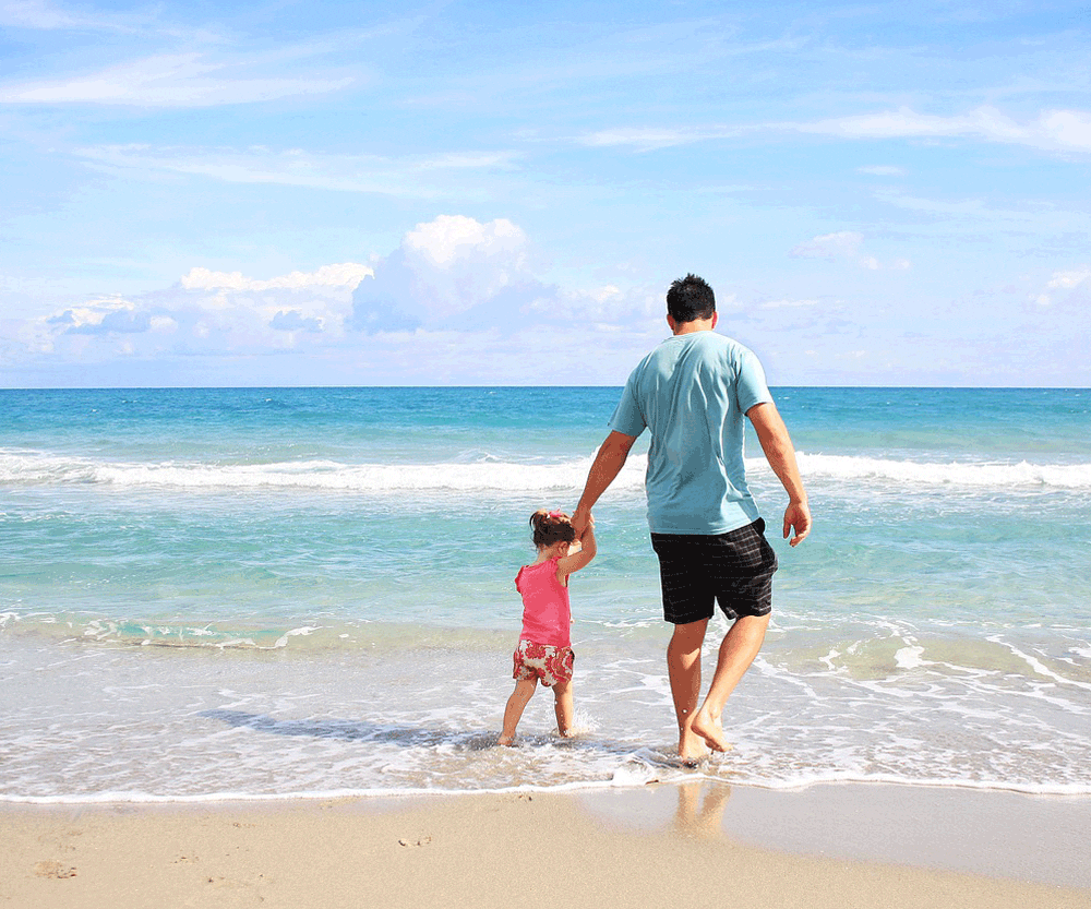 Father with daughter walking on sand while traveling together.