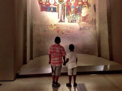Two young boys look up at a painting, while exploring a museum in Barcelona.