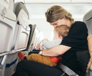 A mom holds her infant son on an airplane.