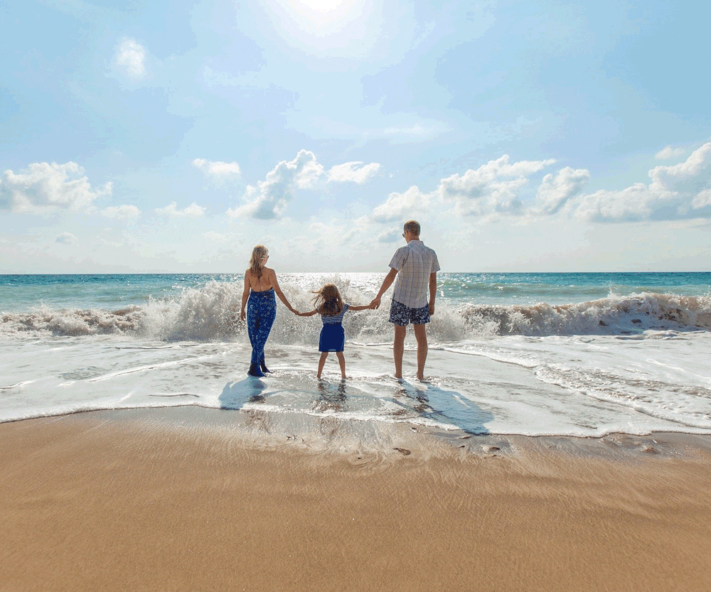 Family with daughter playing in waves on beach