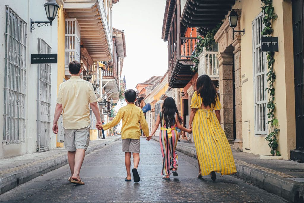 A family of four walks down a road in Cartagena's old town hand-in-hand.