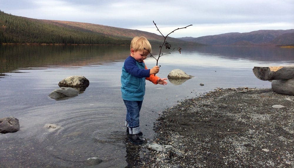 Boy in Denali National Park standing at the edge of the water in one of the best cool-weather destinations in the United States for families.