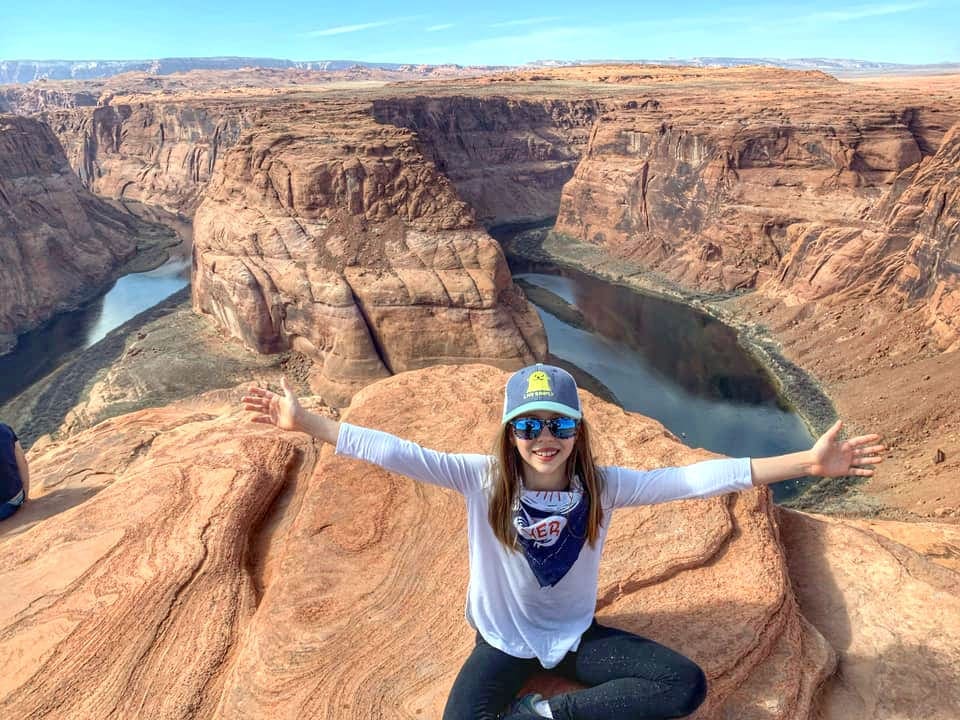 Little Girl posing on top of the Grand Canyon, one of the best affordable summer vacations in the United States with kids.