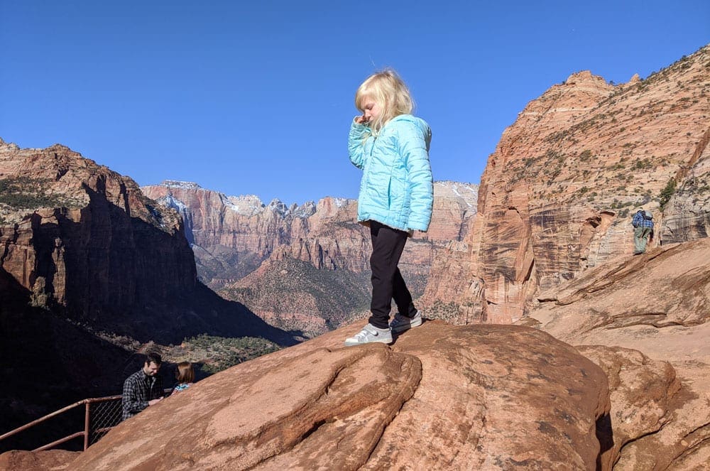 A girl walking over red rocks in Zion National Park, one of the best places to visit on a Grand Canyon itinerary for families. 