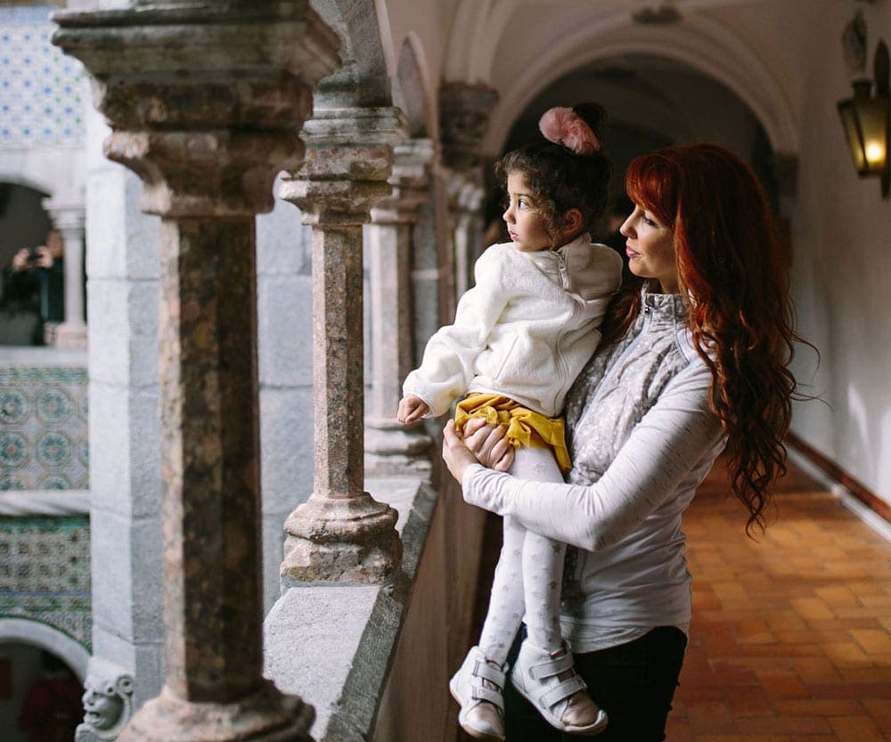 Mom and daughter at Monserrate Palace in Lisbon, looking out across a balcony and plaza.