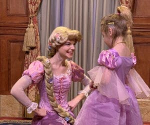 A young girl wearing a Rapunzel dress meets Rapunzel at Magic Kingdom.