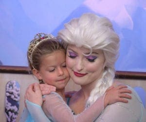 Girl in tiara and princess dress hugging Frozen character Elsa at Disney World. Disney World Kids multi-trip itinerary.