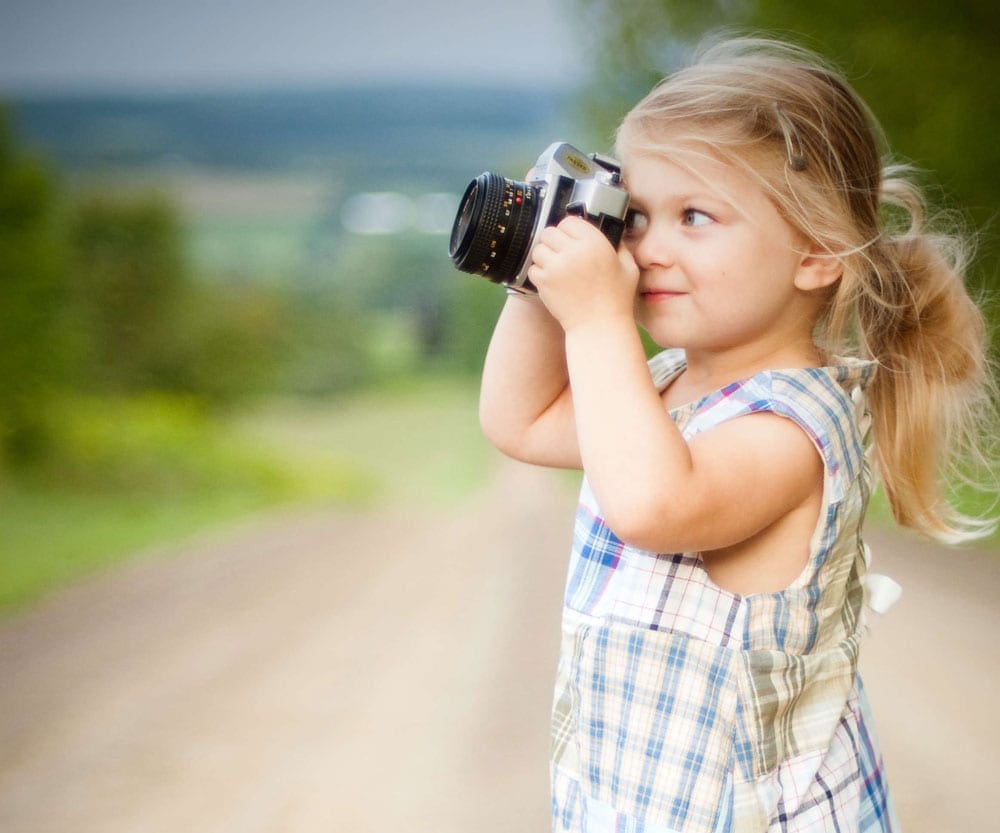 Young girl in dress taking a picture with a professional camera