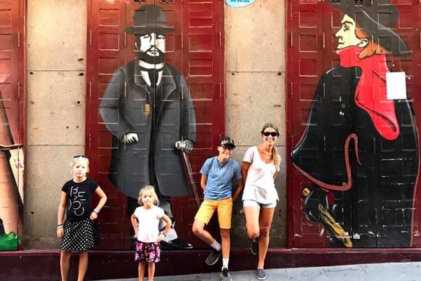 A mom and her three kids stand in front of a street art mural in Madrid.