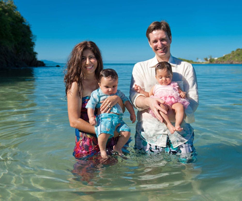 Family with twin babies standing in water in Antigua.