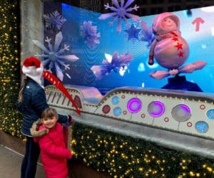 Two young kids look at a Christmas window display in NYC.