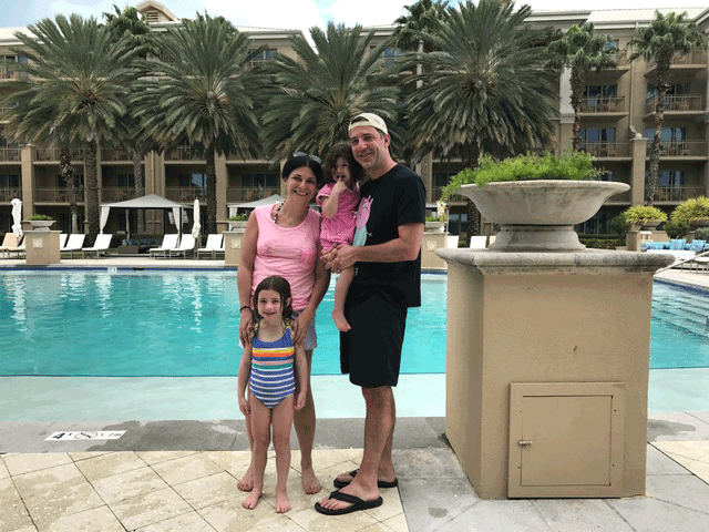 Family with two girls posing poolside at Ritz-Carlton, Grand Cayman.