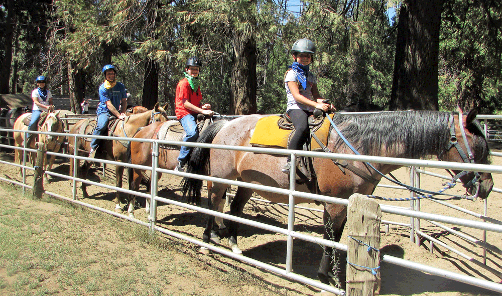 Family horseback riding with helmets at Yosemite National Park.