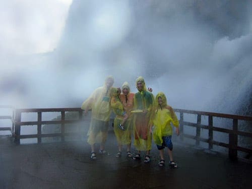 A family posing in Niagara Falls wearing rain ponchos. 