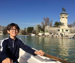 Boy with glasses rowing boat in water in Madrid