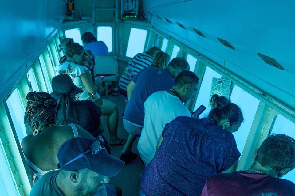 Inside an Atlantis Submarine, people peer out their personal window into the ocean, searching for marine life.