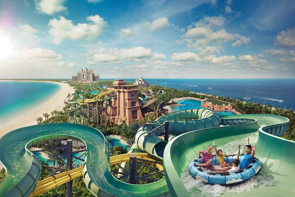 A family enjoys a water slide while sitting in a large tube going down a slide at Atlantis Water Park.