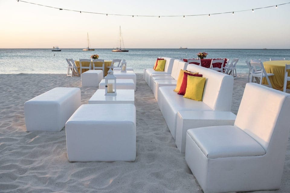 White chairs and loungers sit on the beach access point from Hilton Aruba Caribbean Resort & Casino.