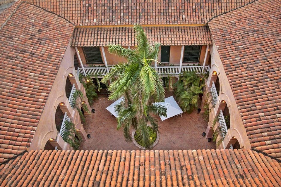 An aerial view of a courtyard within Hotel Charleston Santa Teresa, showcasing a cozy sitting area and lush palm trees.