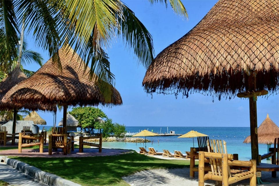 A view of the beach, several cabanas, and umbrella areas on the ground of the Hotel Punta Faro, certainly a great option for those wondering where to stay in Cartagena with kids.