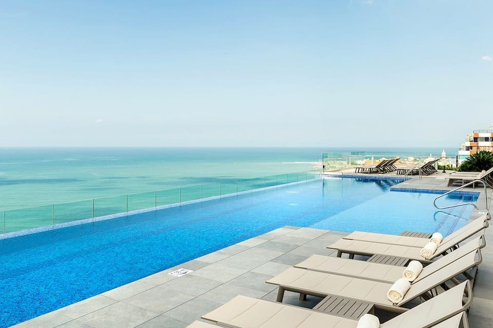 The terrace-level pool at the Hyatt Regency Cartagena, featuring a view of the ocean and several pool-side chairs.