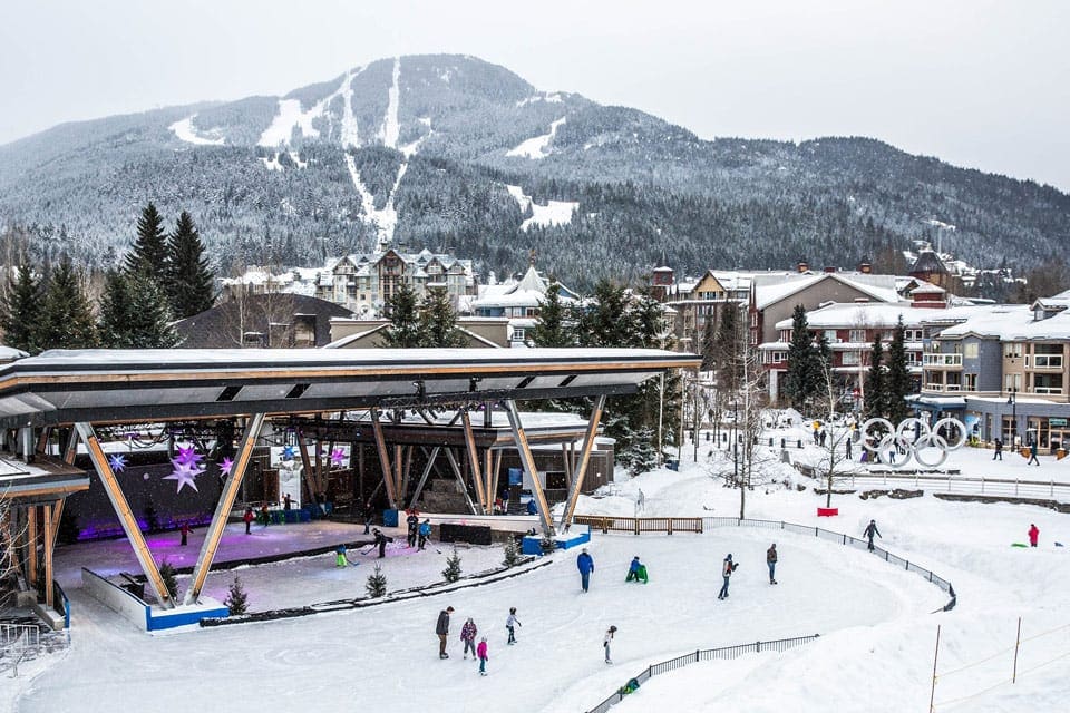 An aerial view of the Whistler Skating Rink on a beautiful day with mountains in the background.