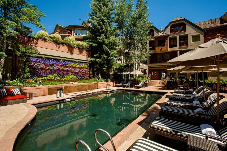 The cozy outdoor pool at The Little Nell during the summer, with an empty pool deck and loungers around the pool.