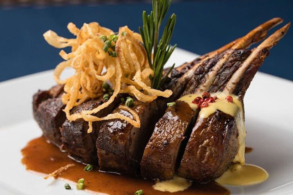 A plate of food, featuring meat still on the bone, at Madame Janette, one of the best restaurants In Aruba for families.