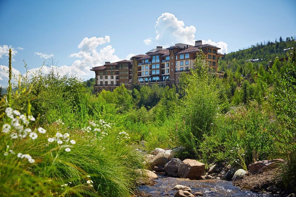 A view of Viceroy Snowmass surrounded by lush greenery and wild flowers during the summer.
