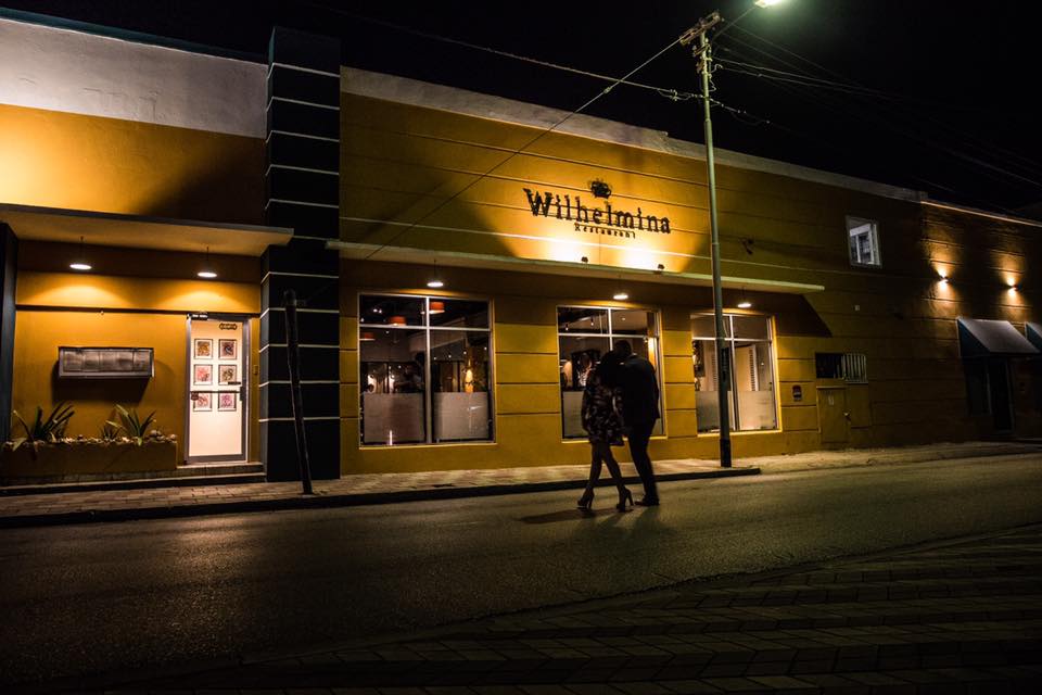 A couple passes the entrance to Wilhelmina Restaurant at night.