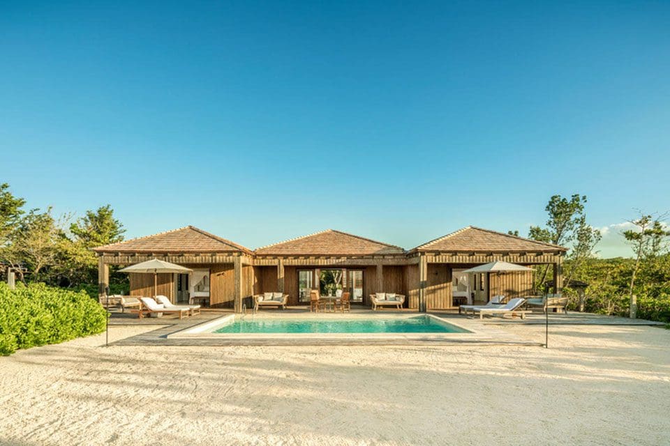 Three inviting cabanas sit behind a calm, blue pool at COMO Parrot Cay, Turks and Caicos.