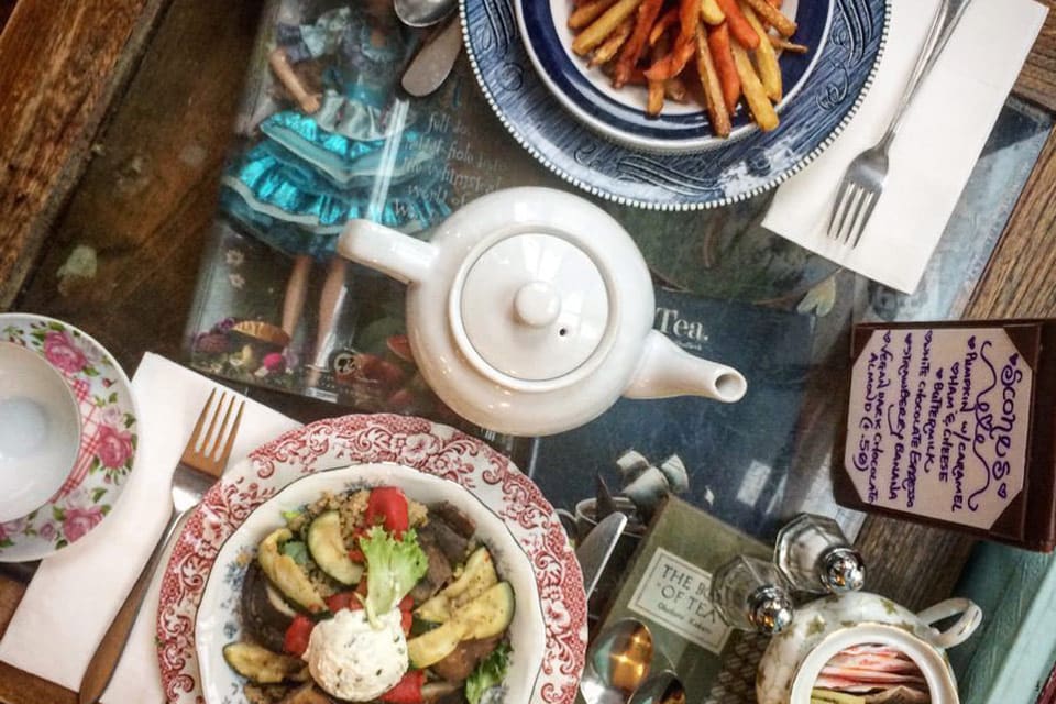 Looking down on a table hosting a tea pot, magazine, and food items at Alice's Tea Cup, one of the most unique New York City restaurants with Kids.