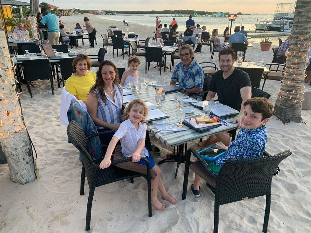 A family enjoys a meal on the beach in Aruba at sunset.