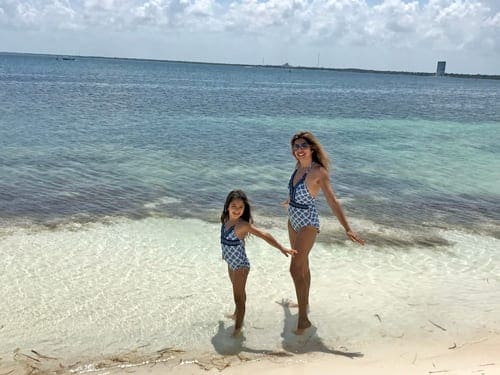 A girl and her mom enjoy a day at the beach in Cacun, one of the best hot places to visit in December for families.