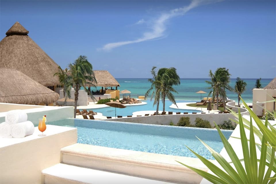 Beautiful view of the pool and the ocean from Fairmont Mayakoba, one of the best all-inclusive resorts Playa del Carmen for families.