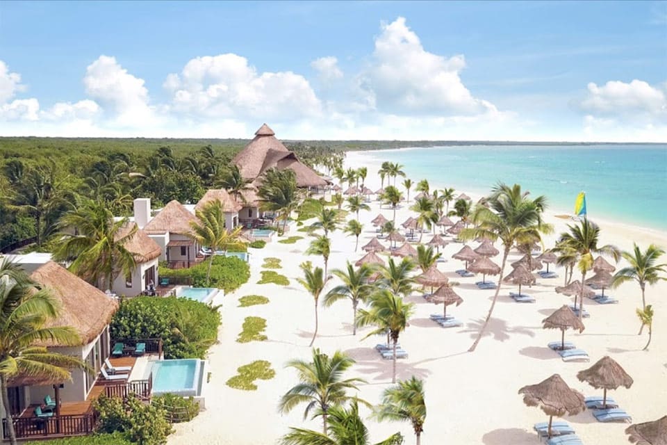 Beautiful beach with villas, palm trees at Fairmont Mayakoba, one of the best hotels in Mexico with large rooms for families.