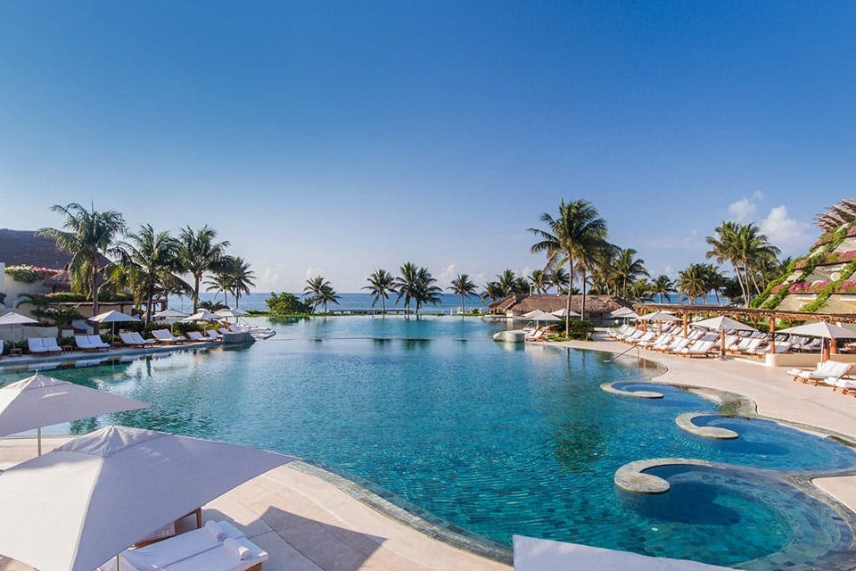 The pool and pool deck, featuring cabanas, at Grand Velas Riviera Maya, one of the best all-inclusive resorts Playa del Carmen for families.