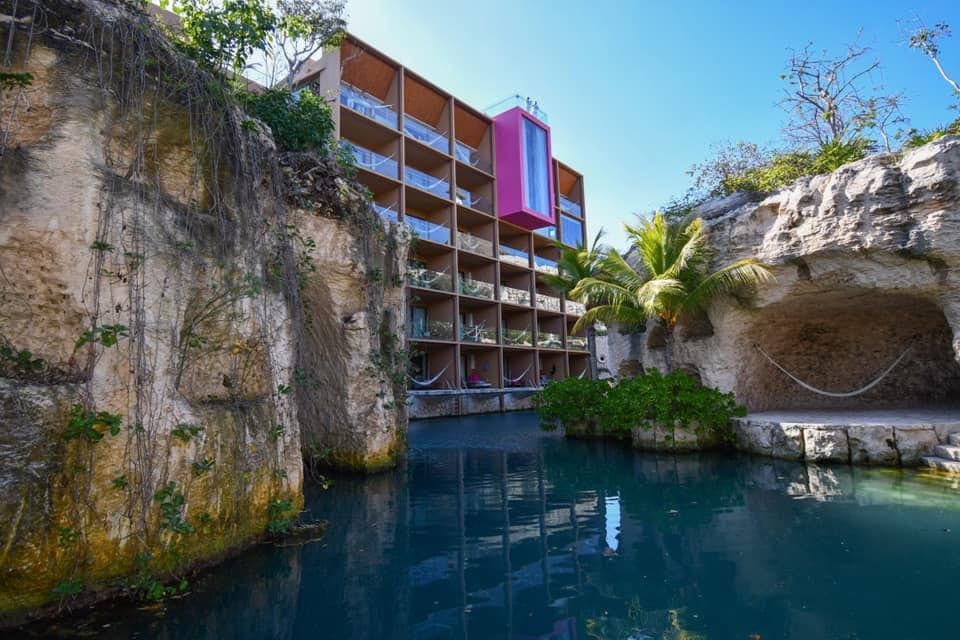 A small pool ebbs through large stones outside the hotel building for Hotel Xcaret Mexico, one of the best resorts in Mexico with a water park for families.