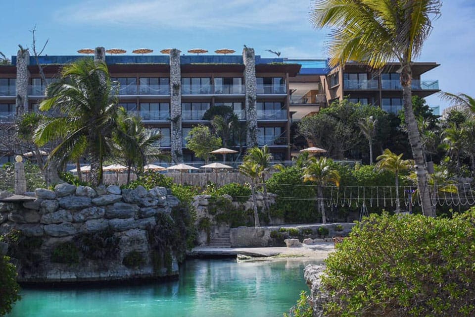 The pool and surrounding pool deck at Hotel Xcaret, with resort buildings in the distance.