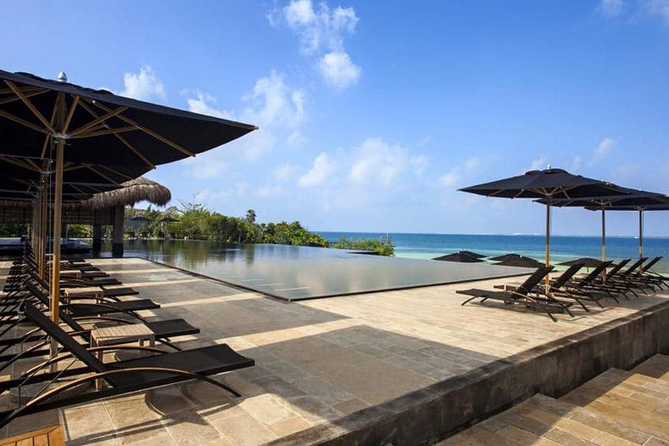 A scenic view of the garden pool villas at NIZUC Resort and Spa, one of the best family resorts Cancun, all of which have an infinity pool along with a waterfall and a bedroom suite.