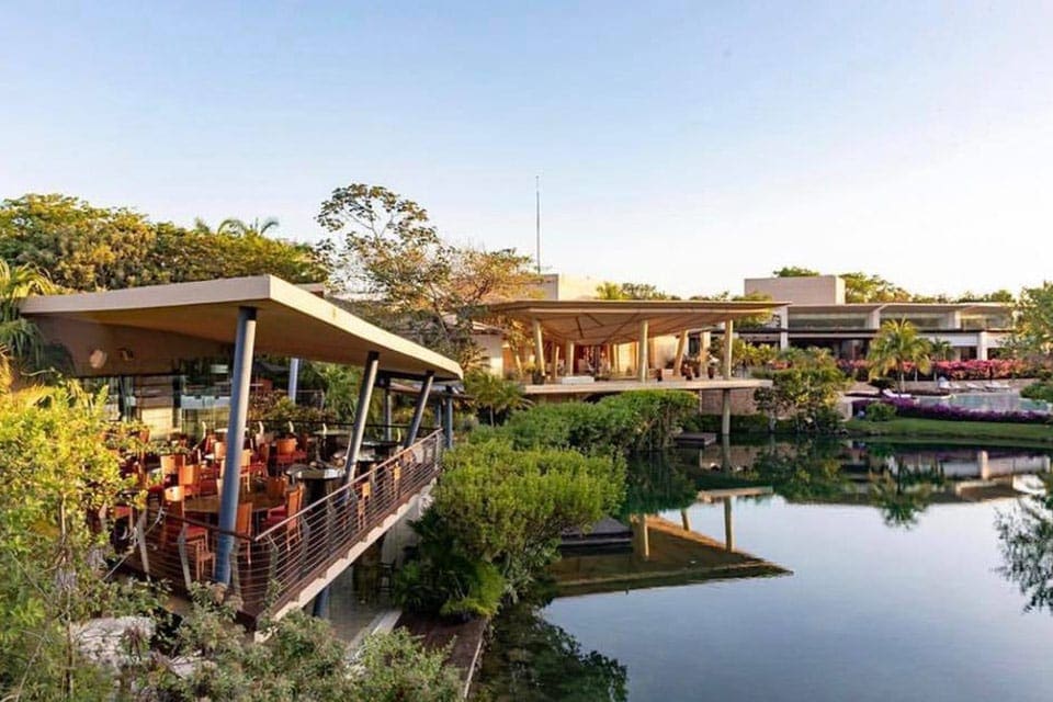 The beautiful lagoon at the Rosewood Mayakoba, one of the best resorts in Mexico for families, flanked by a restaurant and other hotel buildings.