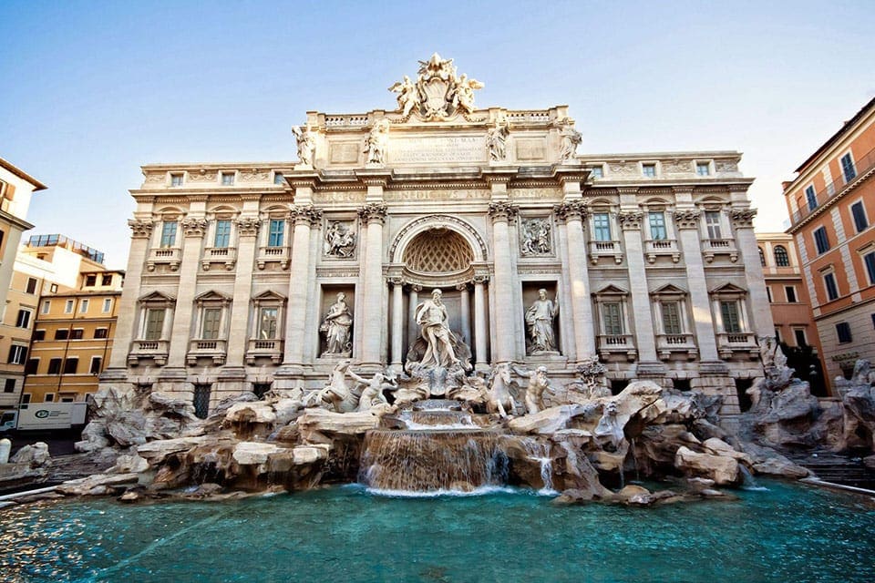The Trevi Fountain in Rome under a blue sky.